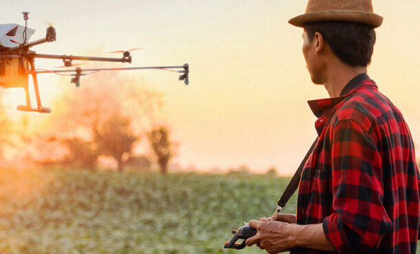 Ein Mann steht auf einem Feld und steuert eine landwirtschaftliche Drohne.
