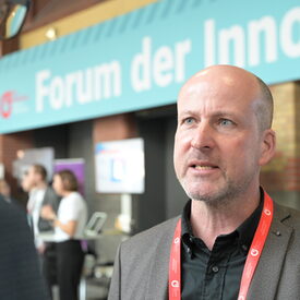 Vertreter der vhs mittleren Alters im Gespräch mit einem Messebesucher