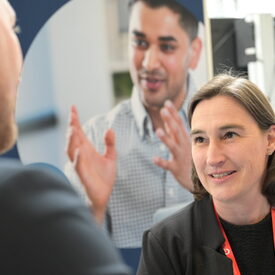 Vertreterin der vhs mittleren Alters im Gespräch mit einem Messebesucher