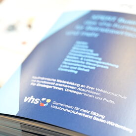 Nahaufnahme eines Buches. Zu sehen ist die Rückseite mit der Aufschrift "Gemeinsam für mehr Bildung. Volkshochschulverband Baden-Württemberg"