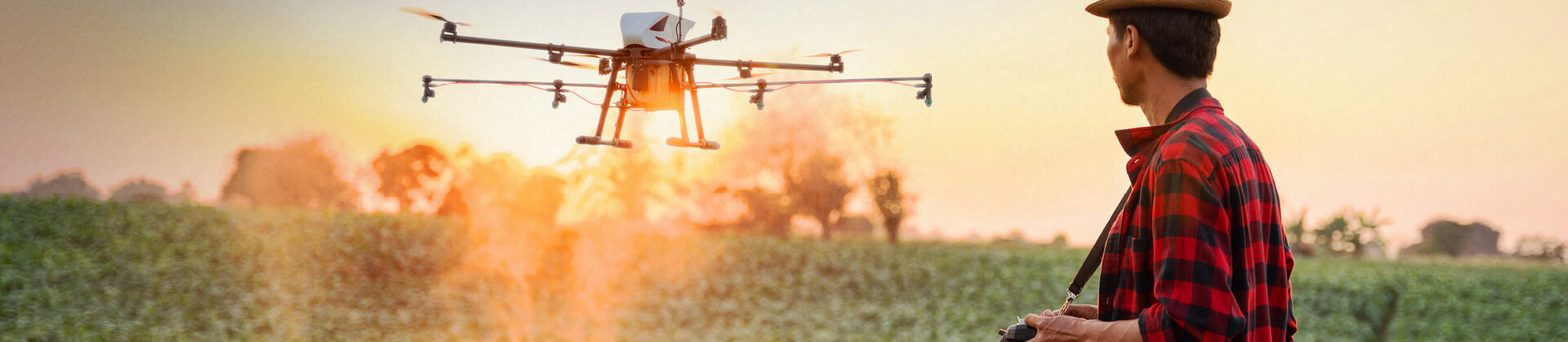 Ein Mann steht auf einem Feld und steuert eine landwirtschaftliche Drohne.