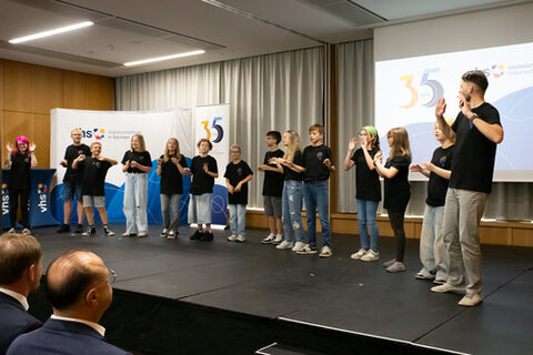 Eine Gruppe Kinder führt auf einer Bühne einen Tanz auf.