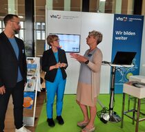 DVV-Präsidentin Annegret Kramp-Karrenbauer lässt sich auf dem Volkshochschultag in Leipzig am Stand des DVV den neuen Lernbereich "Nachhaltigkeit" der App Stadt | Land | DatenFluss vorstellen.
