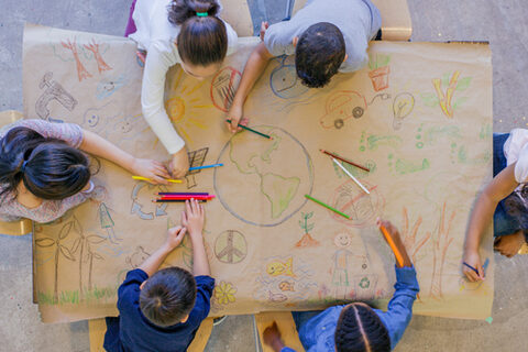 Kinder zeichnen Erdkugel auf Plakat.