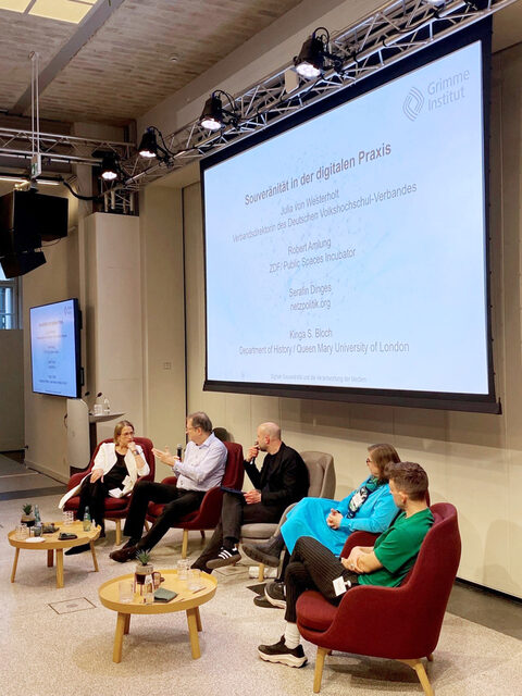 Blick auf ein Podium mit drei Männern und zwei Frauen