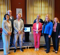 Personengruppe steht zusammen mit einer Bühne und einem Rednerpult im Hintergrund.