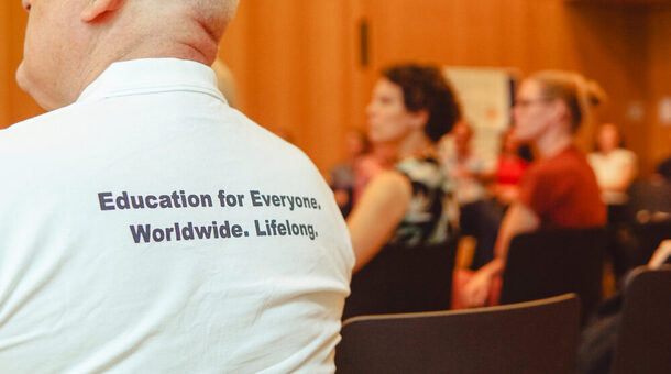 Fotos des Rückens eines Mannes, auf dessen T-Shirt steht "Education für Everyone. Worldwide. Lifelong.