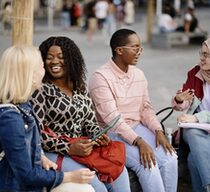 Group of multiethnic students laughing and talking while studying outside