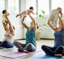 Drei Frauen machen Yoga und halten ihre Babys in die Höhe