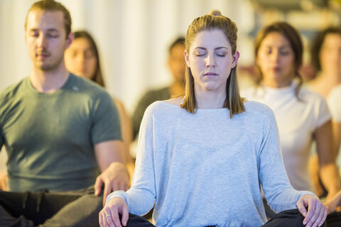 Männer und Frauen meditieren im Sitzen